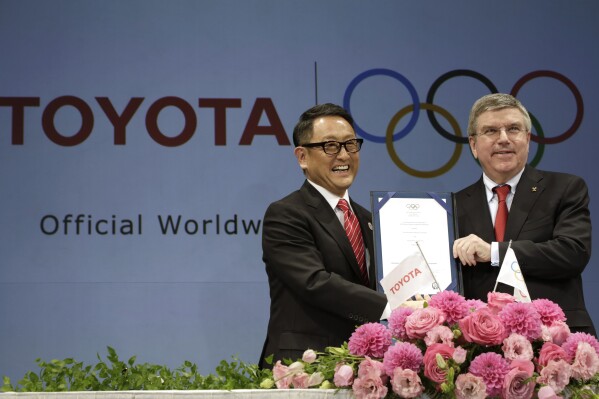 FILE - Toyota President and CEO Akio Toyoda, left, and IOC President Thomas Bach pose with a signed document during a press conference in Tokyo, on March 13, 2015 as Toyota signed on as a worldwide Olympic sponsor in a landmark deal, becoming the first car company to join the IOC's top-tier marketing program. Toyota will end its massive sponsorship deal with the International Olympic Committee after this year's Paris Olympics, according to reports in Japan. (AP Photo/Eugene Hoshiko, File)