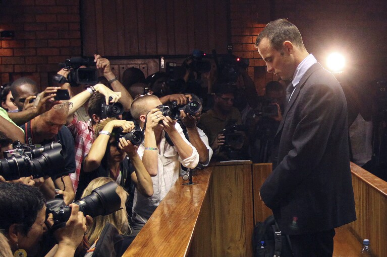 ARCHIVO - Fotógrafos toman fotografías del atleta olímpico Oscar Pistorius mientras comparece en una audiencia de fianza por la muerte a tiros de su novia Reeva Steenkamp, ​​en Pretoria, Sudáfrica, el 22 de febrero de 2013. Oscar Pistorius debe presentarse el viernes 5 de enero. 2024 saldrá de prisión en libertad condicional para vivir bajo estrictas condiciones en una casa familiar después de cumplir casi nueve años de su sentencia de asesinato por la muerte a tiros de su novia Reeva Steenkamp el día de San Valentín de 2013. (Foto AP/Themba Hadebe, archivo)
