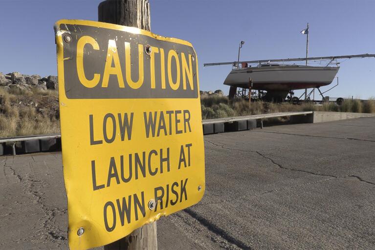 A "CAUTION LOW WATER LAUNCH AT OWN RISK" sign is displayed at the Great Salt Lake Marina on June 3, 2021, near Salt Lake City. The boats were removed this year to keep them from getting stuck in the mud. (AP Photo/Rick Bowmer)