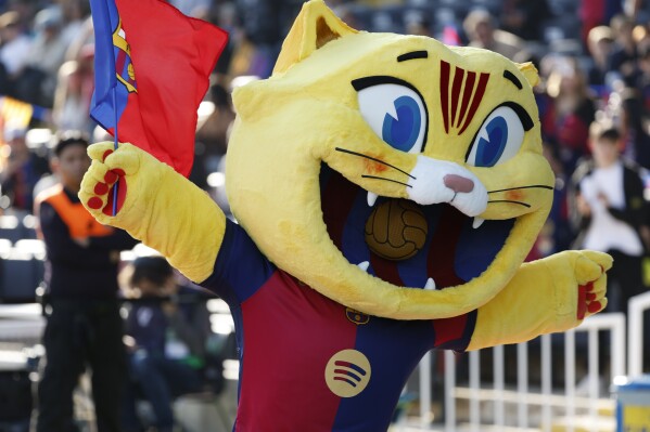 Barcelona's mascot Cat waves a flag prior to a Spanish La Liga soccer match against Las Palmas at the Lluis Companys Olympic Stadium in Barcelona, Spain, Saturday Nov. 30, 2024. (AP Photo/Joan Monfort)