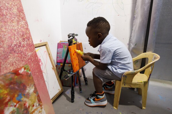 2024年5月27日，星期一，将于7月满两周岁的埃斯·利亚姆·娜娜·萨姆·安卡拉（Ace-Liam Nana Sam Ankrah）在加纳阿克拉（Accra）他母亲的美术馆画画。安卡拉创下了世界上最年轻男艺术家的纪录。他的母亲Chantelle Kukua Eghan说，这一切都是偶然开始的，当时她6个月大的儿子发现了她的颜料。（美联社照片/Misper Apawu）