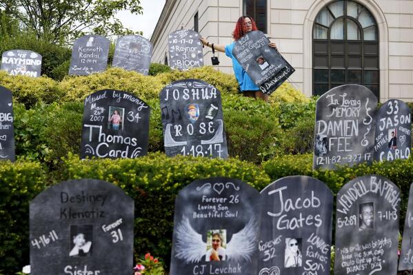 FILE - Jayde Newton helps to set up cardboard gravestones with the names of victims of opioid abuse outside the courthouse where the Purdue Pharma bankruptcy is taking place in White Plains, N.Y., on Aug. 9, 2021. A three-judge panel of the 2nd U.S. Circuit Court of Appeals in New York on Tuesday, May 30 overturned a lower court’s 2021 ruling that found bankruptcy courts did not have the authority to protect members of the Sackler family who own the company and who have not filed for bankruptcy protection from lawsuits. (AP Photo/Seth Wenig, File)