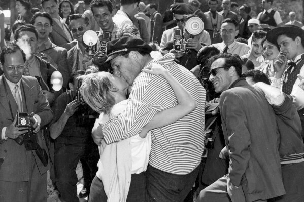 In this April 28, 1955 file photo actor and singer Eddie Constantine kisses his new wife Helene Mussel for the photographers surrounding during the International Film festival in Cannes, France. It is one of the indelible moments the Cannes Film Festival has created throughout its history, and more were likely to be made when it opened on Tuesday, May 12, 2020. This year's festival has been postponed due to the coronavirus pandemic. (AP Photo/Babout, File)