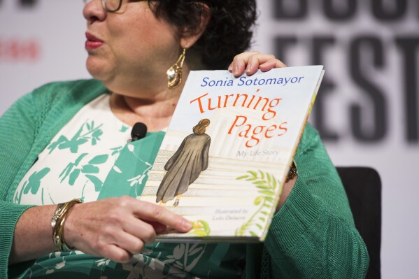 FILE - Supreme Court Justice Sonia Sotomayor holds her children's book, "Turning Pages: My Life Story", while speaking to an audience at the Library of Congress National Book Festival in Washington, Sept. 1, 2018. (AP Photo/Cliff Owen, File)