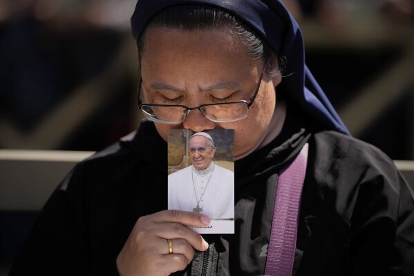 A nun holds a photo of Pope Francis while attending his funeral in St. Peter's Square at the Vatican, Saturday, April 26, 2025. (AP Photo/Andreea Alexandru)
