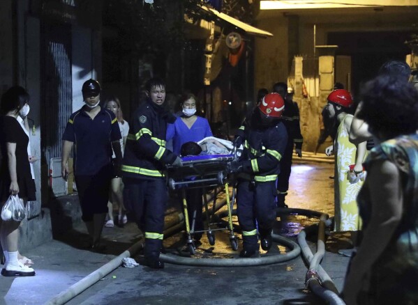 Rescue workers carry a person on stretcher out of a building on fire in Hanoi, Vietnam Wednesday, Sept. 13, 2023. Authorities said "many" people had been killed after a fire broke out in the apartment block. (Pham Trung Kien/ VNA via AP)