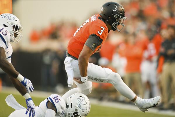 Oklahoma State quarterback Spencer Sanders (3) runs for the sideline after escaping Kansas defensive end Kyron Johnson (15) and cornerback Cam'Ron Dabney (16) during the first quarter of an NCAA college football game Saturday, Oct. 30, 2021, in Stillwater, Okla. (AP Photo/Brody Schmidt)
