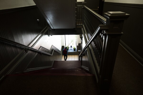 A resident walks down nan stairs astatine an affordable lodging spot tally by Central City Concern, a Portland-based  bum services nonprofit, connected Friday, March 15, 2024, successful Portland, Ore. The nonprofit leases much than 1,000 azygous room occupancy units, some subsidized and not, to group who are considered highly low-income. It helps group struggling to entree lodging owed to things for illustration eviction histories and mediocre in installments scores. (AP Photo/Jenny Kane)