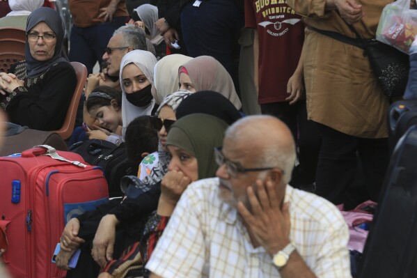 Palestinians wait at the Rafah border crossing between the Gaza Strip and Egypt Gaza Strip on Saturday, Oct. 14, 2023. Israel carried out some limited ground operations ahead of an expected broader land offensive against Gaza's militant Hamas rulers following their attack into southern Israel a week ago. (AP Photo/Hatem Ali)