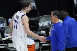 FILE- In this Sunday, June 6, 2021, file photo, Dallas Mavericks guard Luka Doncic (77) slaps hands with owner Mark Cuban after losing in Game 7 of an NBA basketball first-round playoff series against the Los Angeles Clippers in Los Angeles, Calif. Cuban is suddenly without a coach and general manager after the Mavericks were a model of stability in the NBA for more than a decade. The owner's next moves figure to be all about superstar Luka Doncic following coach Rick Carlisle's decision to quit a day after the club announced the departure of longtime GM Donnie Nelson. (AP Photo/Ashley Landis, File)