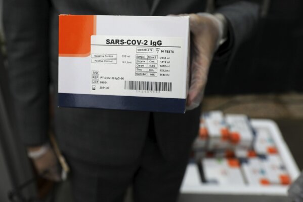A medical firm staff holds a coronavirus testing kit in a medical firm, just outside Tehran, Iran, Saturday, April 11, 2020. A medical firm outside west of Tehran launched the production line of serology-based test kits that can discover whether a person has ever been exposed to the novel coronavirus or suffered from the COVID-19 disease and recovered or not. (AP Photo/Ebrahim Noroozi)