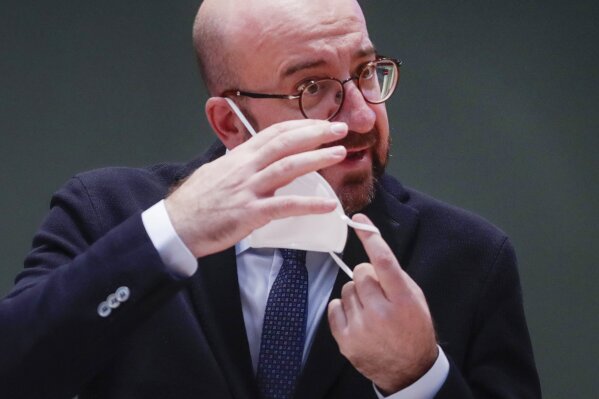 European Council President Charles Michel takes off his protective face mask as he prepares to take part in an EU Summit, via videoconference link, at the European Council building in Brussels, Thursday, Feb. 25, 2021. European Union leaders are gathering Thursday, via videoconference link, to try to inject new energy into the 27-nation bloc's lagging coronavirus vaccination effort as concern mounts that new variants might spread faster than authorities can adapt. (Olivier Hoslet, Pool via AP)
