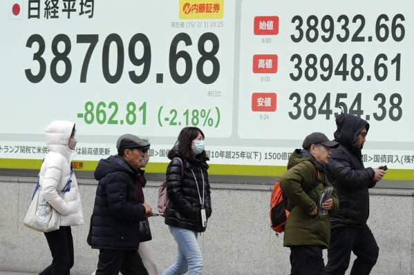 People walk in front of an electronic stock board showing Japan's Nikkei index at a securities firm Monday, Feb. 3, 2025, in Tokyo. (AP Photo/Eugene Hoshiko)