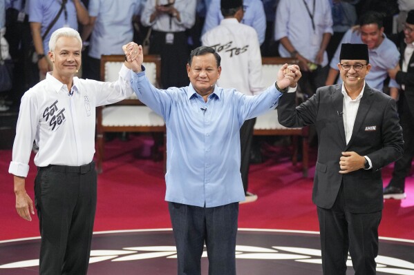 FILE - Presidential candidates, from left, Ganjar Pranowo, Prabowo Subianto and Anies Baswedan holds hands as they pose for photographers after the first presidential candidates' debate in Jakarta, Indonesia, Tuesday, Dec. 12, 2023. Indonesia, the world's third-largest democracy, will open its polls on Wednesday to nearly 205 million eligible voters in presidential and legislative elections, the fifth since Southeast Asia's largest economy began democratic reforms in 1998. (AP Photo/Tatan Syuflana, File)