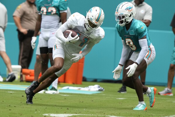 Miami Dolphins wide receiver Cedrick Wilson Jr., left, runs with the ball as safety Jevon Holland (8) defends during an NFL football scrimmage at Hard Rock Stadium, Saturday, Aug. 5, 2023, in Miami Gardens, Fla. (AP Photo/Lynne Sladky)