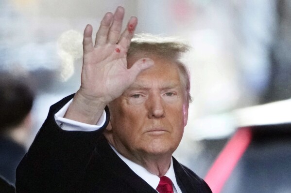 Former President Donald Trump waves as he leaves his apartment building in New York, Wednesday, Jan. 17, 2024. With Trump looking on, writer E. Jean Carroll testified Wednesday that the former president shattered her reputation and continues to inspire venom against her from strangers because she claimed he sexually abused her decades ago. (AP Photo/Seth Wenig)