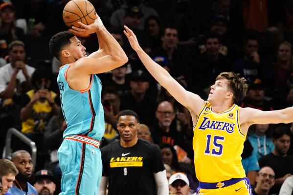 Phoenix Suns' Devin Booker shoots a three pointer against Los Angeles Lakers' Austin Reaves (15) during the first half of an NBA basketball game in Phoenix, Tuesday, Nov. 22, 2022. (AP Photo/Darryl Webb)
