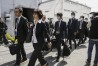 Japan's health ministry officials walk towards the Osaka plant of Kobayashi Pharmaceutical Co. to conduct an on-site inspection in Osaka, western Japan, Saturday, March 30, 2024. Japanese government health officials raided a factory Saturday producing health supplements that they say have killed multiple people and hospitalized more than 100 others.