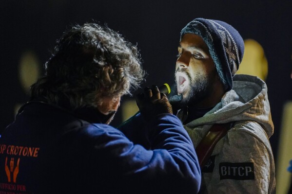 Migrants disembark from the SOS Humanity 1 humanitarian ship in the Italian southern port town of Crotone, Monday, March 4, 2023. German charity SOS Humanity said the Libyan coast guard used violence and fired live bullets as its crew rescued migrants in the Mediterranean Sea on Saturday. The charity said that several migrants aboard three unseaworthy boats had to jump into the water. It said that it rescued 77 people, but that others were forced aboard a coast guard vessel. Some family members were separated and at least one migrant drowned. (Antonino D'Urso/LaPresse via AP )