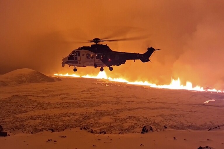 Dieses Bild aus einem von der isländischen Küstenwache bereitgestellten Video zeigt ihren Hubschrauber, der in der Nähe von Magma fliegt und irgendwann am späten Montag, dem 18. Dezember, oder frühen Dienstag, dem 19. Dezember 2023, einen Hügel in der Nähe von Grindavik auf der Reykjanes-Halbinsel in Island hinunterläuft. Ein Vulkanausbruch hat begonnen .  In der Nacht zum Montag verfärbte sich der Himmel auf der isländischen Halbinsel Reykjanes orange und löste beim Zivilschutz des Landes höchste Alarmbereitschaft aus.  (Isländische Küstenwache über AP)