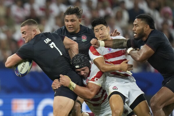 England's Ben Earl, is brought down by Japan's Pieter Labuschagne, at bottom, during the Rugby World Cup Pool D match between England and Japan in the Stade de Nice, in Nice, France Sunday, Sept. 17, 2023. (AP Photo/Pavel Golovkin)