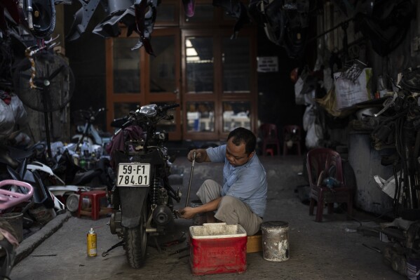 A mechanic works on a scooter at a repair shop in Ho Chi Minh City, Vietnam, Jan. 13, 2024. (AP Photo/Jae C. Hong)