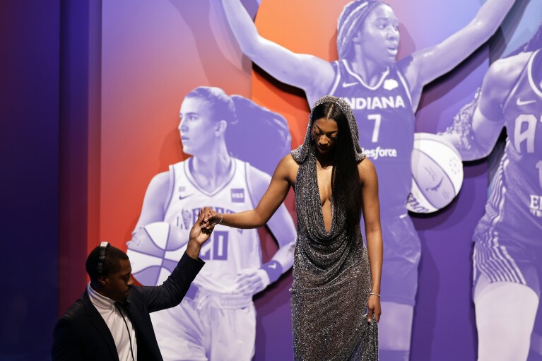 LSU's Angel Reese, right, is helped off the stage after being selected seventh overall by the Chicago Sky during the first round of the WNBA basketball draft on Monday, April 15, 2024, in New York. (AP Photo/Adam Hunger)