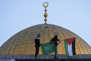 FILE - Masked Palestinians carry Palestinian and Hamas flags during Eid al-Fitr celebrations next to the next to the Dome of the Rock Mosque in the Al-Aqsa Mosque compound in the Old City of Jerusalem, May 2, 2022. The Palestinian militant group Hamas is threatening hostile actions against Israel over what it called “violations against Jerusalem and the Al-Aqsa Mosque” ahead of the upcoming Jewish High Holidays. Hamas’ threats on Thursday, Sept. 22, 2022, came just ahead of the Jewish new year on Sunday and a day after a group of Jewish religious extremists visited the contested holy site. (AP Photo/Mahmoud Illean, File)
