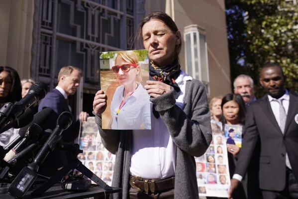 FILE - Catherine Berthet, of France, closes her eyes as she holds a photo of her deceased daughter Camille Geoffroy, in front of other families that lost loved ones to crashes of the Boeing 737 Max airliner outside the federal court in Fort Worth, Texas, Thursday, Jan. 26, 2023. Relatives of passengers who died in two Boeing Max crashes are pushing federal officials to prosecute the company, but they're not getting any promises from the Justice Department.(AP Photo/LM Otero, file)