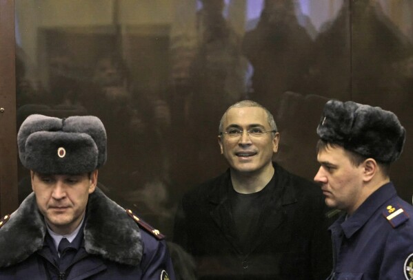 FILE – Oil tycoon and Kremlin political opponent Mikhail Khodorkovsky, center, is seen in a defendants’ cage in court in Moscow, Russia, Thursday, Dec. 30, 2010, during a trial on financial crimes. Over the last decade, Vladimir Putin's Russia evolved from a country that tolerates at least some dissent to one that ruthlessly suppresses it. Arrests, trials and long prison terms — once rare — are commonplace. (AP Photo, File)