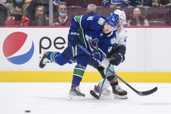Vancouver Canucks' Elias Pettersson, front left, of Sweden, and Seattle Kraken's Yanni Gourde vie for the puck during the first period of an NHL hockey game in Vancouver, British Columbia, Monday, Feb. 21, 2022. (Darryl Dyck/The Canadian Press via AP)