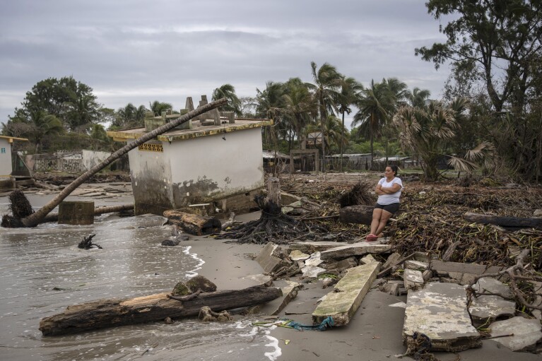 Guadalupe Cobos sits along the shore amid debris caused by flooding driven by a Gulf of Mexico sea-level rise, in her coastal community of El Bosque, in the state of Tabasco, Mexico, Wednesday, Nov. 29, 2023. (AP Photo/Felix Marquez)