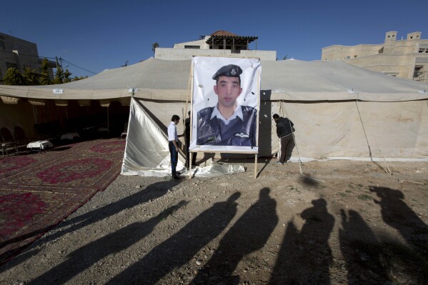 In this Friday, Jan. 30, 2015 file photo, workers raise a banner with a photo of Jordanian pilot Lt. Mu’ath al-Kaseasbeh, held captive by the Islamic State group, outside a tent for supporters in Amman, Jordan. (AP Photo/Nasser Nasser file)