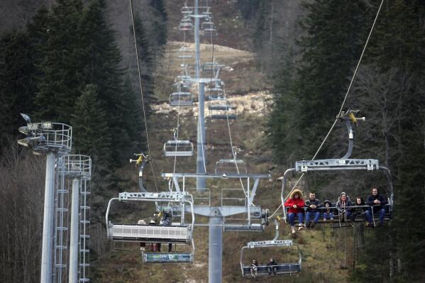 People ride the cable car above the ski track without any snow on Bjelasnica mountain near Sarajevo, Bosnia, Wednesday, Jan. 4, 2023. (AP Photo/Armin Durgut)