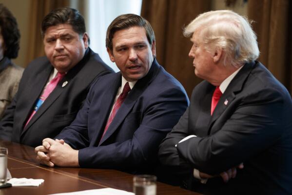 FILE - Gov.-elect Ron DeSantis, R-Fla., talks with President Donald Trump during a meeting with newly elected governors in the Cabinet Room of the White House, Dec. 13, 2018, in Washington. From left, Governor-elect J.B. Pritzker, D-Ill., DeSantis, and Trump. (AP Photo/Evan Vucci, File)