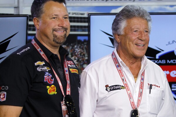 FILE - Michael Andretti, left, and his father, Mario Andretti, pose for a photo following a news conference at Texas Motor Speedway in Fort Worth, Texas, June 7, 2013. Formula One has rejected Andretti Global's application to join the global racing series in 2025 or 2026 but said Wednesday, Jan. 31, 2024, it is willing to revisit the issue in 2028 when General Motors has an engine ready for competition.(AP Photo/Tim Sharp, File)