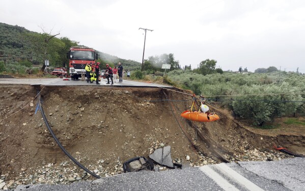Firefighters use ropes to lift a kidney patient in a stretcher across a road damaged by a rainstorm in Kala Nera village, near Volos, central Greece, Wednesday, Sept. 6, 2023. The death toll from severe rainstorms that lashed parts of Greece, Turkey and Bulgaria increased Wednesday after rescue teams located the body of a missing vacationer who was swept away by flood waters that raged through a campsite in northwest Turkey. (AP Photo/Thodoris Nikolaou)