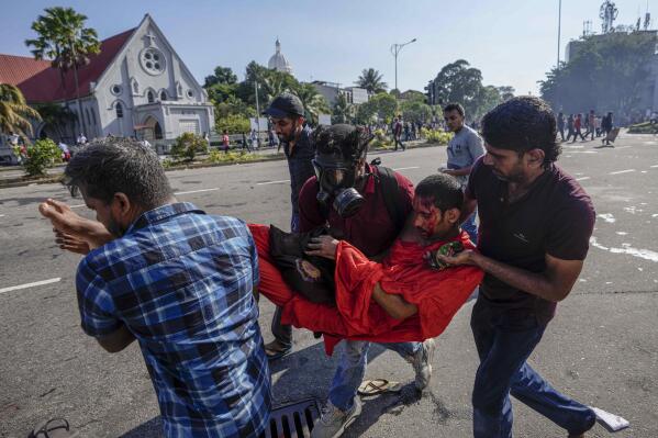 Members of Sri Lankan opposition political party National People's Power carry an injured Buddhist monk during a clash with police in Colombo, Sri Lanka, Sunday, Feb. 26, 2023. The opposition supporters were protesting over a decision to postpone local elections after the government said it cannot finance the same because of the country's crippling economic crisis. (AP Photo/Eranga Jayawardena)