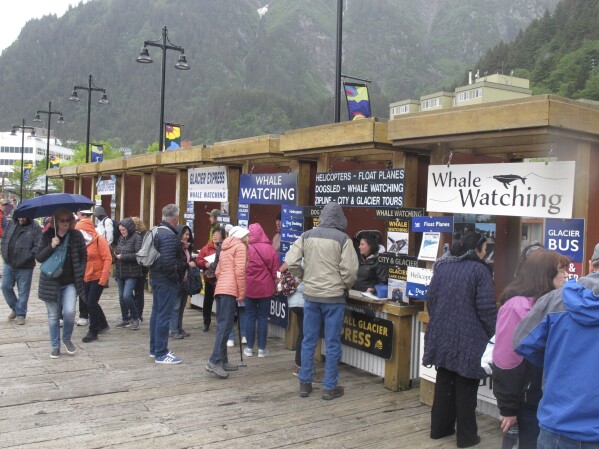 Tourists stop at booths along the sea walk on June 12, 2023, in downtown Juneau, Alaska, where they can book activities to do while they're in town. (AP Photo/Becky Bohrer)