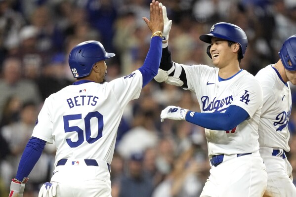 Los Angeles Dodgers' Shohei Ohtani, right, is congratulated by Mookie Betts after hitting a two-run home run during the sixth inning of a baseball game against the Texas Rangers Tuesday, June 11, 2024, in Los Angeles. (AP Photo/Mark J. Terrill)