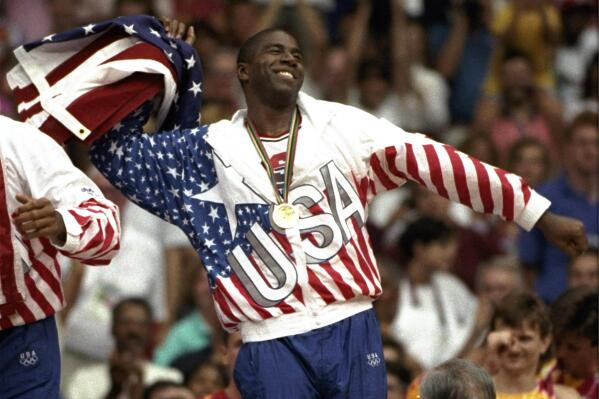 FILE - USA's Earvin "Magic" Johnson the United States flag celebrates during the gold medal ceremony Saturday, Aug. 8, 1992, during the 1992 Summer Olympic games in Barcelona. The "Dream Team" with the first U.S. Olympic men's basketball team to field active NBA players rolls past Croatia 117-85 for the gold medal at the 1992 Barcelona Games. The Americans demolish the field. (AP Photo/Susan Ragan, File)