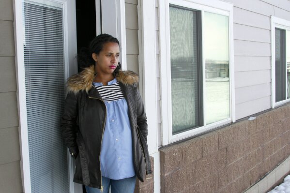 In this April 13, 2020, photo, Kulule Amosa steps out of the apartment she shares with her husband who works at the Smithfield Foods pork processing plant in Sioux Falls, S.D. He tested positive for the coronavirus this week after an outbreak at the plant. (AP Photo/Stephen Groves)