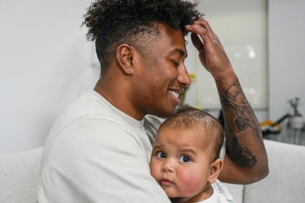 Ellia Green is pictured with his daughter Waitui in Sydney, Australia, Monday, Aug. 15, 2022. Green, one of the stars of Australia's gold medal-winning women's rugby sevens team at the 2016 Olympics, has transitioned to male. The 29-year-old, Fiji-born Green is going public in a video at an international summit aimed at ending transphobia and homophobia in sport. The summit is being hosted in Ottawa as part of the Bingham Cup rugby tournament. (AP Photo/Mark Baker)
