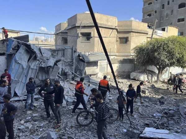 People look at a home that was destroyed by an Israeli airstrike on Dec. 6, 2023, in Nuseirat refugee camp in the Gaza Strip. Four-year-old Omar Abu Kawaik was pulled alive from the rubble and brought out of Gaza then flown to the United States, where he received treatment including a prosthetic arm. (Courtesy of Maha Abu Kuwaik via AP)