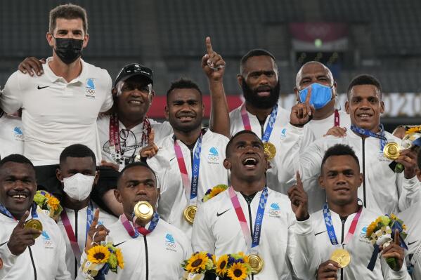 Fiji's players celebrate on the podium with their gold medals in men's rugby sevens at the 2020 Summer Olympics, Wednesday, July 28, 2021 in Tokyo, Japan. (AP Photo/Shuji Kajiyama)