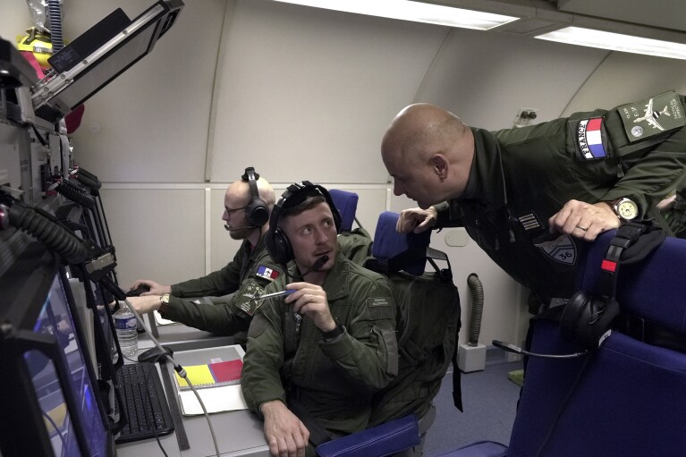 The commander of France's AWACS squadron, a lieutenant colonel named Richard, talks to crew members aboard one of the four French surveillance planes as it flies a 10-hour mission Tuesday, Jan. 9, 2024, to eastern Romania for the NATO military alliance. Because of French security concerns, The Associated Press was only able to identify him and other military personnel aboard the flight by their ranks and first names. Screens in the plane that display intelligence data were marked "secret." (AP Photo/John Leicester)