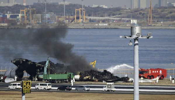 A fumaça preta sobe enquanto o trabalho de remoção é realizado no local de uma colisão de aeronave no Aeroporto de Haneda, em Tóquio, na sexta-feira, 5 de janeiro de 2024. Guindastes estavam desmontando o voo 516 da Japan Airlines, Airbus A350, que pegou fogo após colidir com um avião da Guarda Costeira enquanto eles estavam desmontando o avião.  Ela estava pousando no aeroporto na terça-feira.  (Notícias Kyodo via Associated Press)