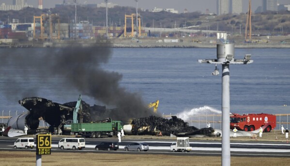 Czarny dym unosi się w miarę kontynuowania prac porządkowych na miejscu katastrofy lotniczej na lotnisku Haneda w Tokio, piątek, 5 stycznia 2024 r.  Dźwigi demontowały samolot Airbus A350 Japan Airlines Flight 516, który wylądował na lotnisku we wtorek.  (Wiadomości z Kioto za pośrednictwem AP)