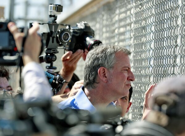
              FILE - In this Thursday, June 21, 2018, file photo, New York City Mayor Bill de Blasio looks through a closed gate at the Port of Entry facility, in Fabens, Texas, where tent shelters are being used to house separated family members. U.S. Customs and Border Protection is alleging that de Blasio illegally crossed from Mexico into the U.S. while visiting the El Paso, Texas, area in June, an accusation the mayor’s office flatly denies. (AP Photo/Matt York, File)
            