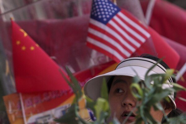 A woman walks past Chinese and United States' national flags on display at a merchandise store in Beijing, Thursday, April 3, 2025. (AP Photo/Andy Wong)